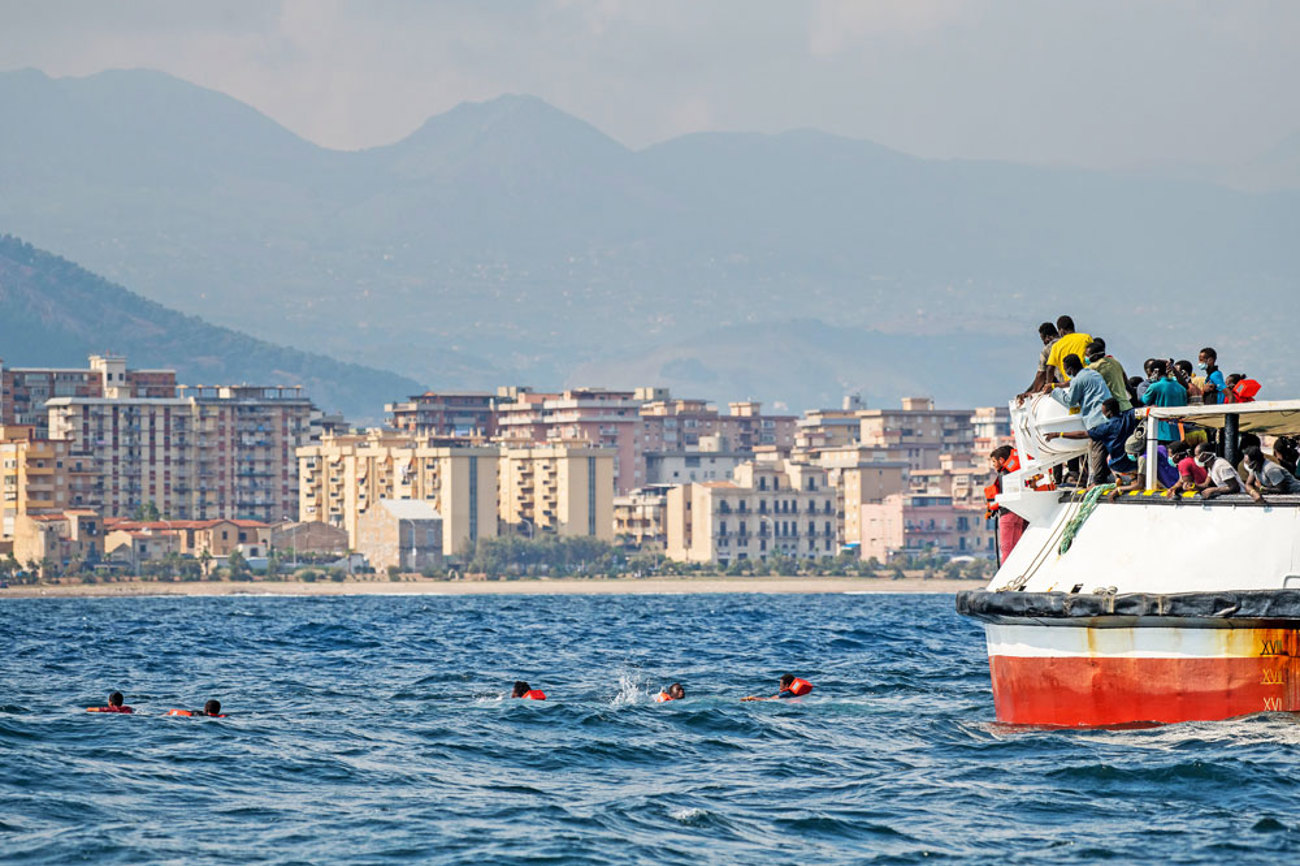Verzweifelte Lage auf dem Rettungsschiff «Open Arms»: Im Versuch, die sizilianische Küste zu erreichen, springen mehrere Dutzend Menschen vom Schiff ins Wasser. Foto: Thomas Lohnes/epd